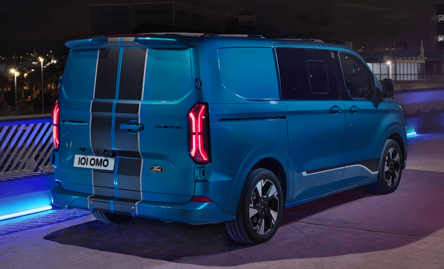 A rear view of the All-New Ford Transit Custom DCIV in blue, parked on a road at night time with blue electric lights on the floor around the van.