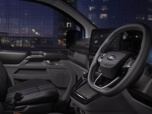 A view across the interior cabin of the All-New Ford Transit Custom DCIV showing the steering wheel, infotainment system, and the digital driver display.